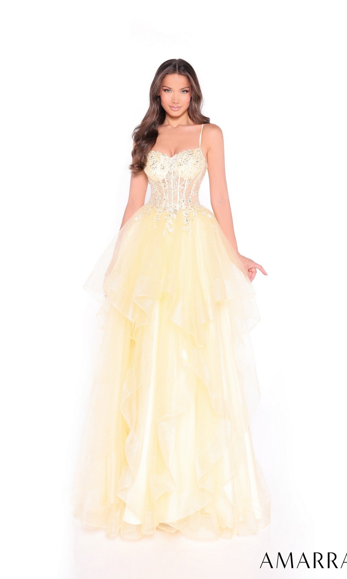 A woman wears the Amarra 89504 Lace-Up Long Tiered Prom Dress in yellow, featuring spaghetti straps, a sheer sequin-embellished bodice, and a layered tulle skirt.